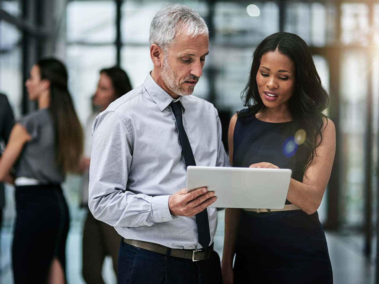 Male and female professional colleagues looking at a tablet together