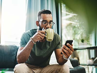 Man drinking coffee looking at his computer