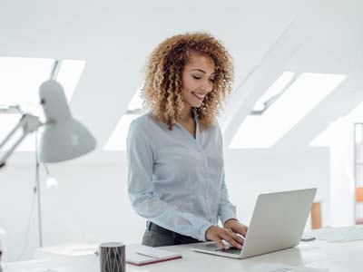 Woman standing and typing on a laptop