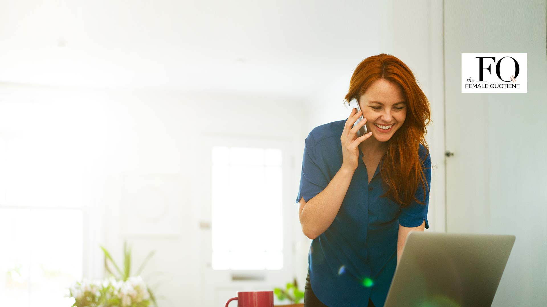 Woman working from home on her laptop talking on the phone