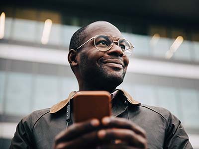 African American man with glasses holding a mobile phone and smiling