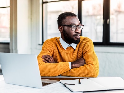 Man with arms folded in front of laptop