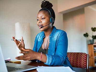 Woman with headset on talking while in front of a computer