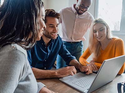 Group of people gathered around a laptop and smiling