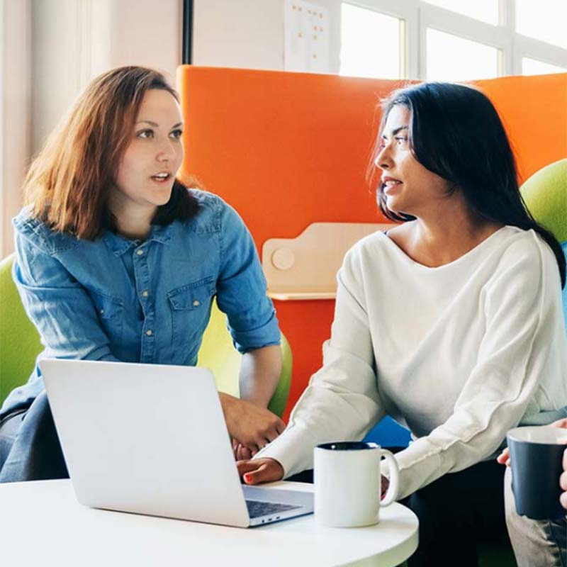 Two coworkers looking at a laptop.