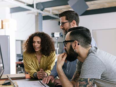 Three people gathered around a computer looking at the screen