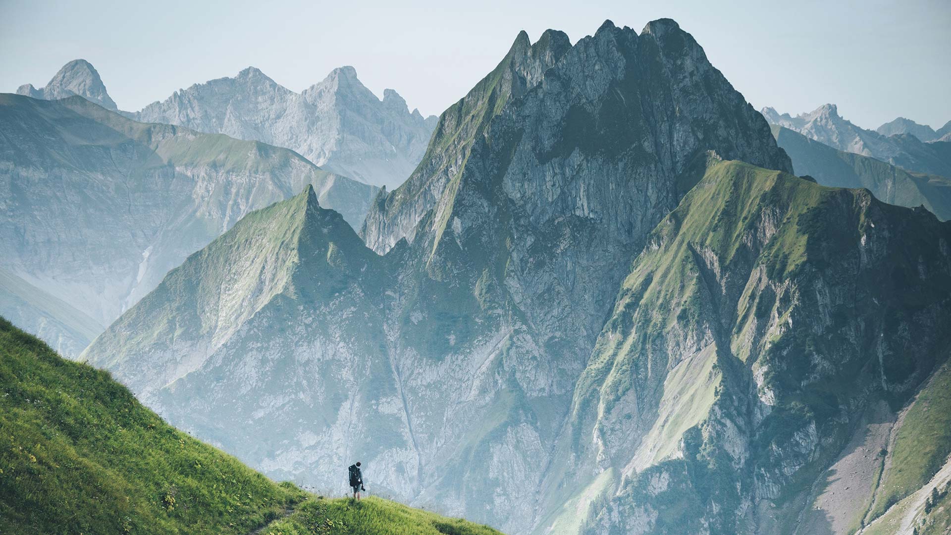 View of mountain range with tiny hiker in the foreground