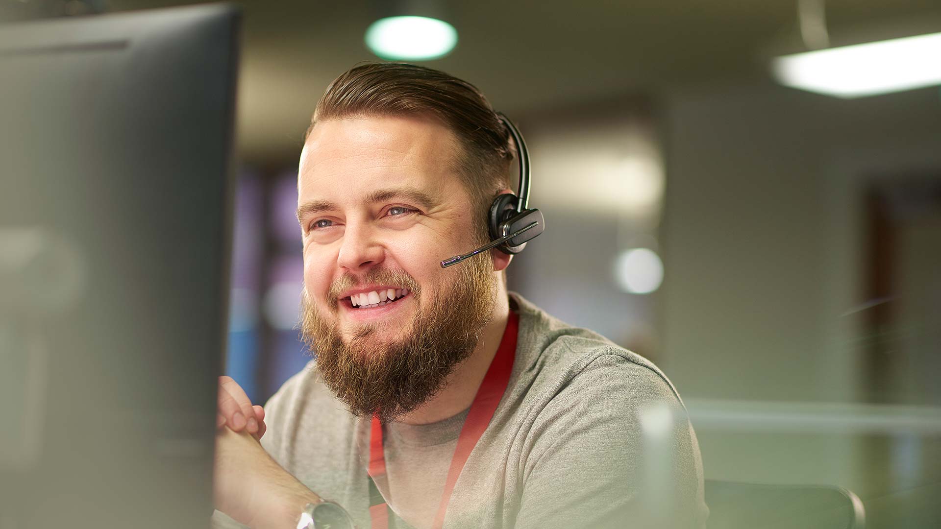 men wearing headset smiling and looking at a computer
