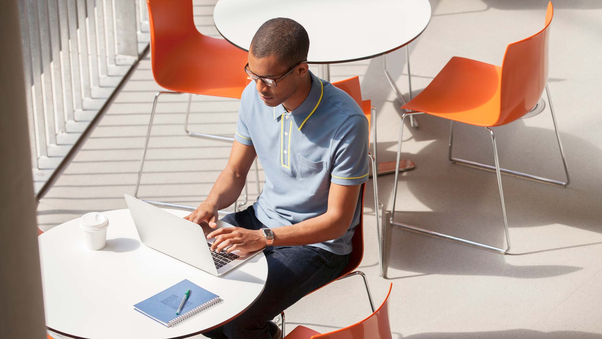 Man sitting at table outdoors, working on laptop