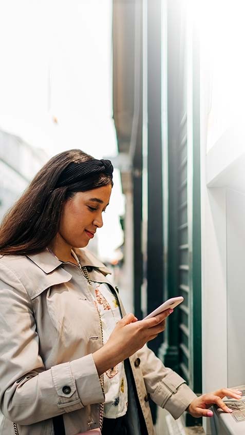 Woman using a ATM machine in a city.