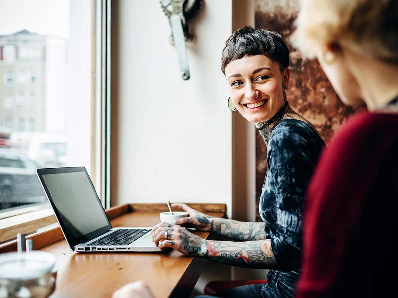 A woman sitting in a bright café talking to a friend.