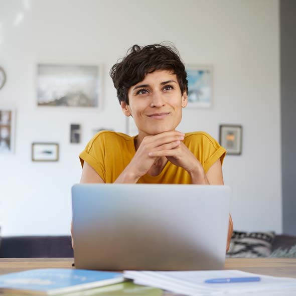 Smiling woman at home sitting at table using laptop