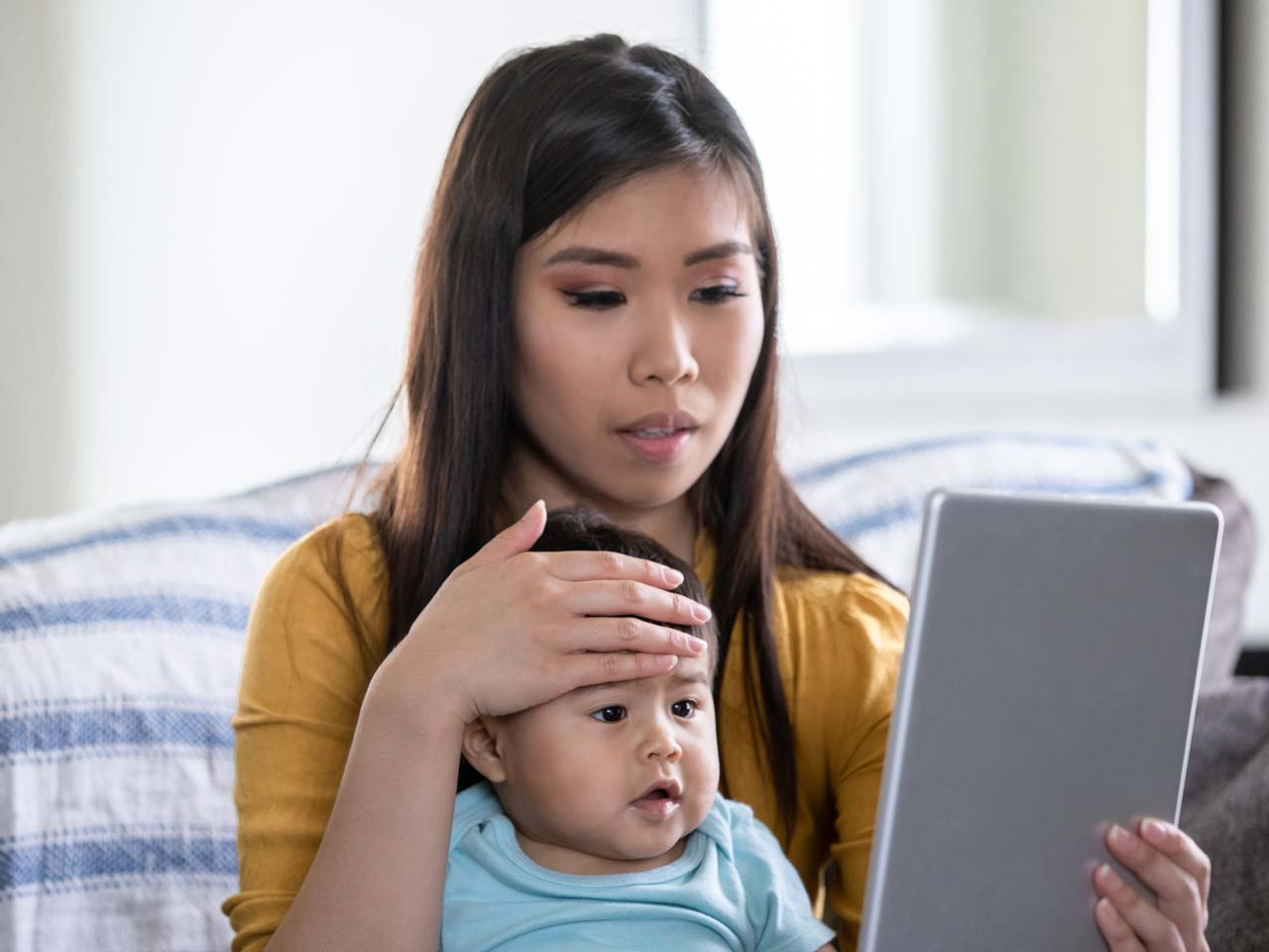 Mother holding a baby while having a conference call with Dr.