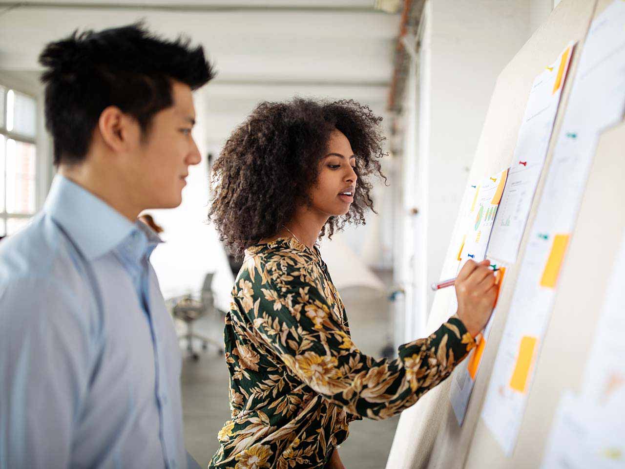 Two coworkers reviewing a whiteboard.